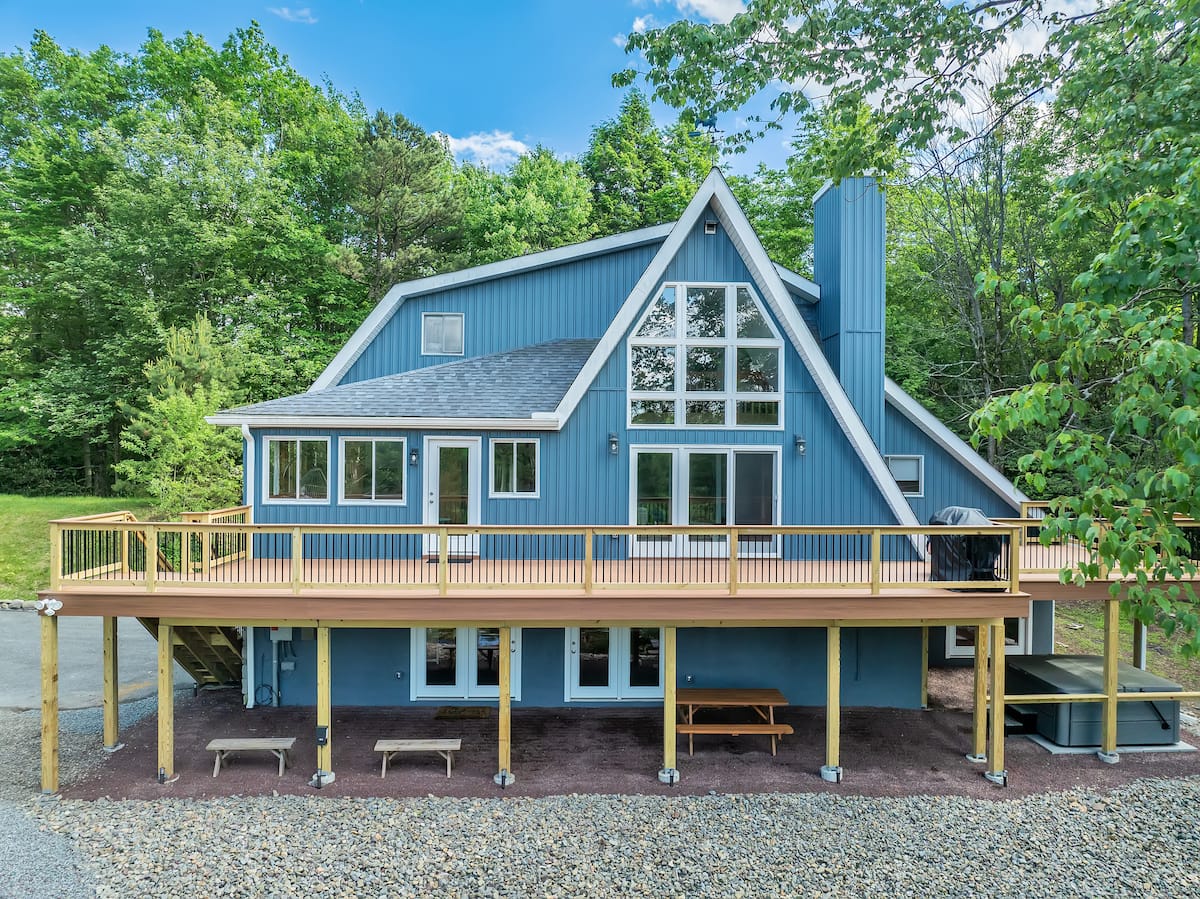 Powderhorn Cove — blue A-frame chalet with expansive wraparound deck, hot tub, and wooded surroundings